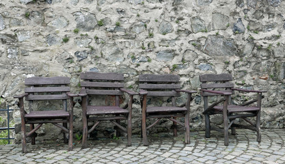 Fototapeta na wymiar Vier rustikale braune Holzstühle vor einer alten Steinmauer