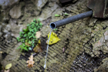 Spring water flows from a metal pipe