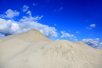 Kopalnia odkrywkowa, góra piasku na tle błękitnego nieba. - obrazy, fototapety, plakaty