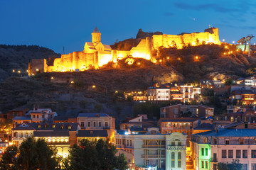 Amazing view of Olt town with Narikala ancient fortress, St Nicholas Church in night Illumination during evening blue hour, Tbilisi, Georgia.