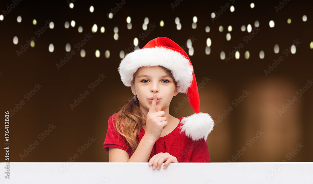 Wall mural girl in santa hat with board making hush gesture 