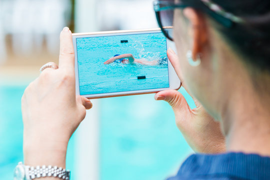 woman taking picture of her son swimming with her smart phone