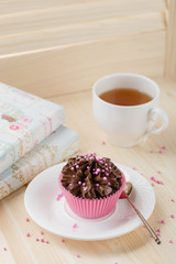 Chocolate cupcake with sprinkles in pink cup