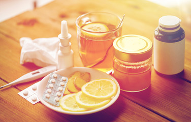 drugs, thermometer, honey and cup of tea on wood