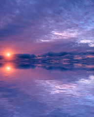 A piece of the sun from behind the clouds during the sunset on the autumn sky above the water.