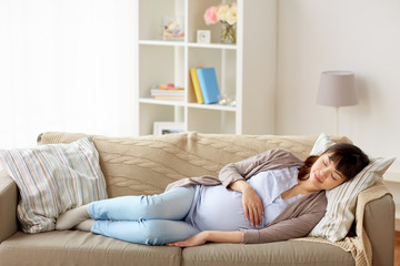 happy pregnant woman sleeping on sofa at home