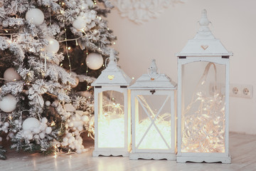 Christmas lantern with ornaments and snow in sepia tone near tree.