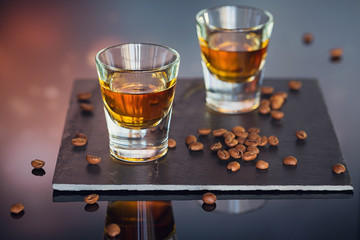 Cognac or liqueur, coffee beans and spices on a glass table.