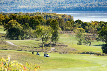 golfers and golf carts on hilly golf course