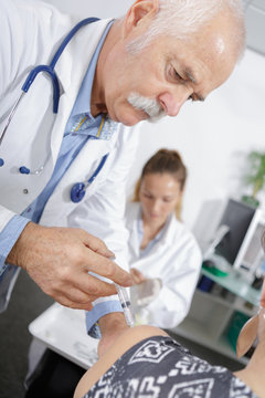 senior doctor giving an injection to a patient