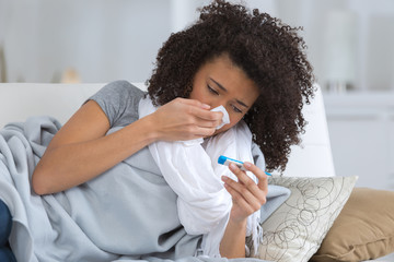 woman with temperature looking at thermometer