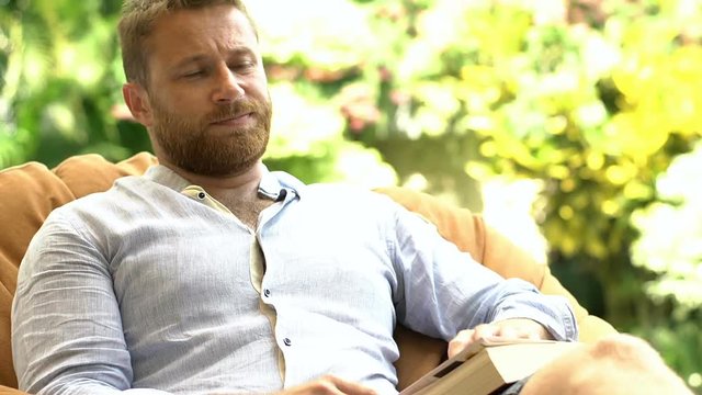 Man finish reading book and sitting on the bean bag chair
