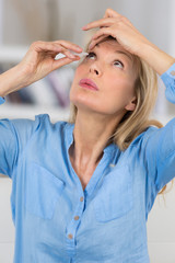 a woman putting eye drops in her eyes