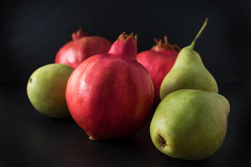 Fresh pomegranate with pears close up on black background