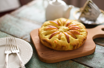 Homemade apple cake with teaware on shabby blue wooden background