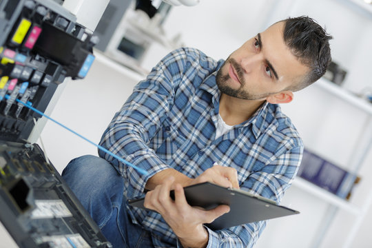 Male technician assessing photocopier