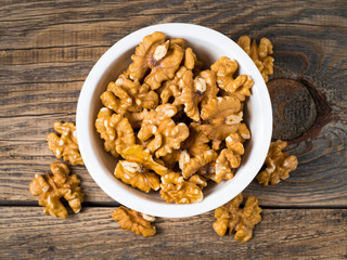 Top view of white cups with walnut, bowls with handful of nuts  on a wooden background