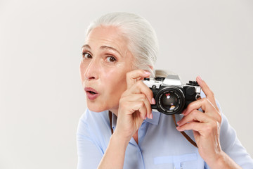 Surprised woman holding retro camera islated over white