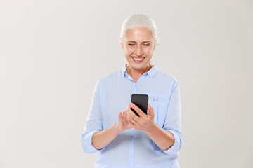 Mature smiling woman using smartphone isolated
