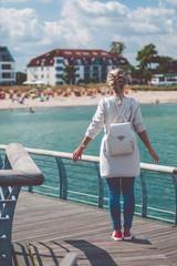 Woomen on pier near beach with roofed wicker chairs in Travemuende at the Baltic Sea. Travepromenade in Travemunde, a borough of Lubeck, Germany