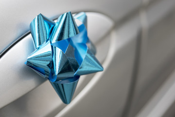 Close up of a blue wedding bow on the handle of a silver wedding car