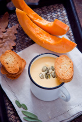 Homemade Pumpkin soup in a white mug and slices of pumpkin