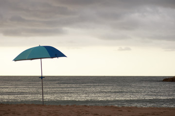 Parasol on a sandy beach along the sea at sunrise