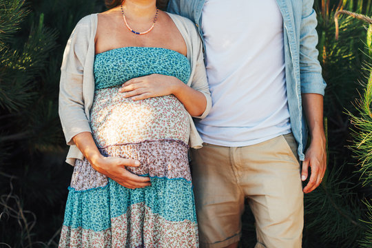 Closeup of a young pregnant couple standing outside.