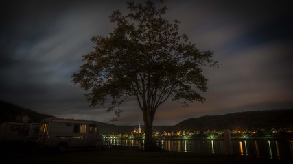 Langzeitbelichtung einer Stadtspiegelung mit Baum im Vordergrund
