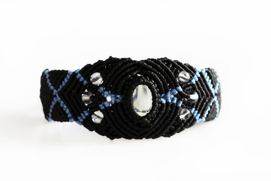 black bracelet on the hand of waxed thread, plastic beads and moonstone in the technique of macrame.