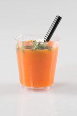cup of tomato gazpacho soup with green pesto sauce, salt and basil