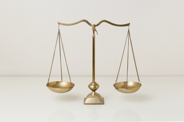 Gold brass balance scale on white glass table. Sign of justice, lawyer
