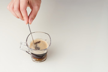 Espresso coffee in glass cup with vintage spoon on white glass table
