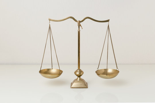 Gold brass balance scale on white glass table. Sign of justice, lawyer
