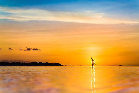 Silhouette man standing in water and the sun sets behind them