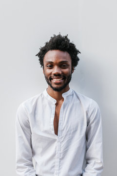 Afro American Man Smiling Over a White Wall