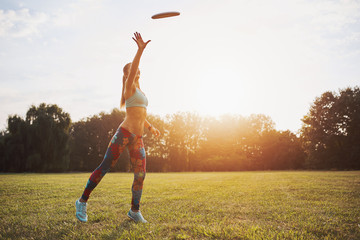 Young athletic girl playing with flying disc, ultimate