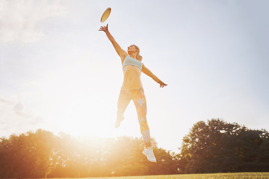 Young athletic girl playing with flying disc, ultimate