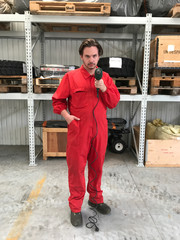 Young mechanic in red suit making jokes with a drill