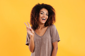 Cheerful african woman showing peace sign and looking at camera
