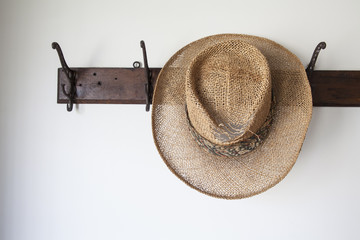 Old straw hat on antique coat rack hook