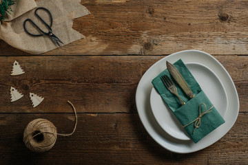 Christmas table setting with folded napkin. Festive dinner table decoration on dark antique wood. Top view.