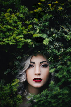 Red lips girl with grey curl hair in green bush