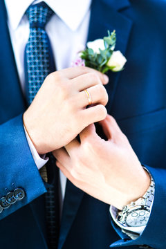 The groom corrects boutonniere on the jacket