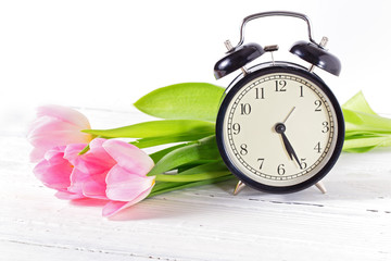 Three pink tulips and alarm clock.