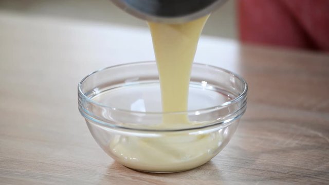 Hot creme being poured into mixing bowl to create a custard mix for a creme brulee dessert.