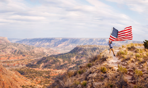 Man waving an American flag while standing on canyon