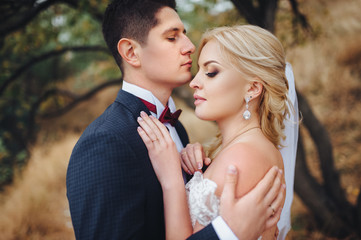 The newlyweds are hugging each other in the autumn forest. Wedding concept. 