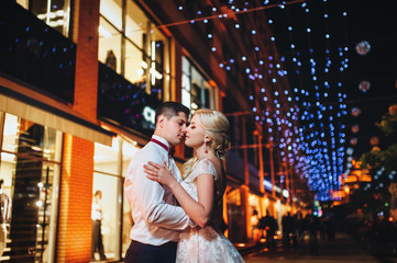 Evening romantic photography of the newlyweds on the streets of the city that lit the lights. 