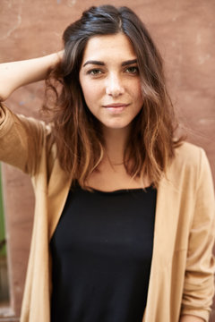 Beautiful girl in beige and black touching her hair.